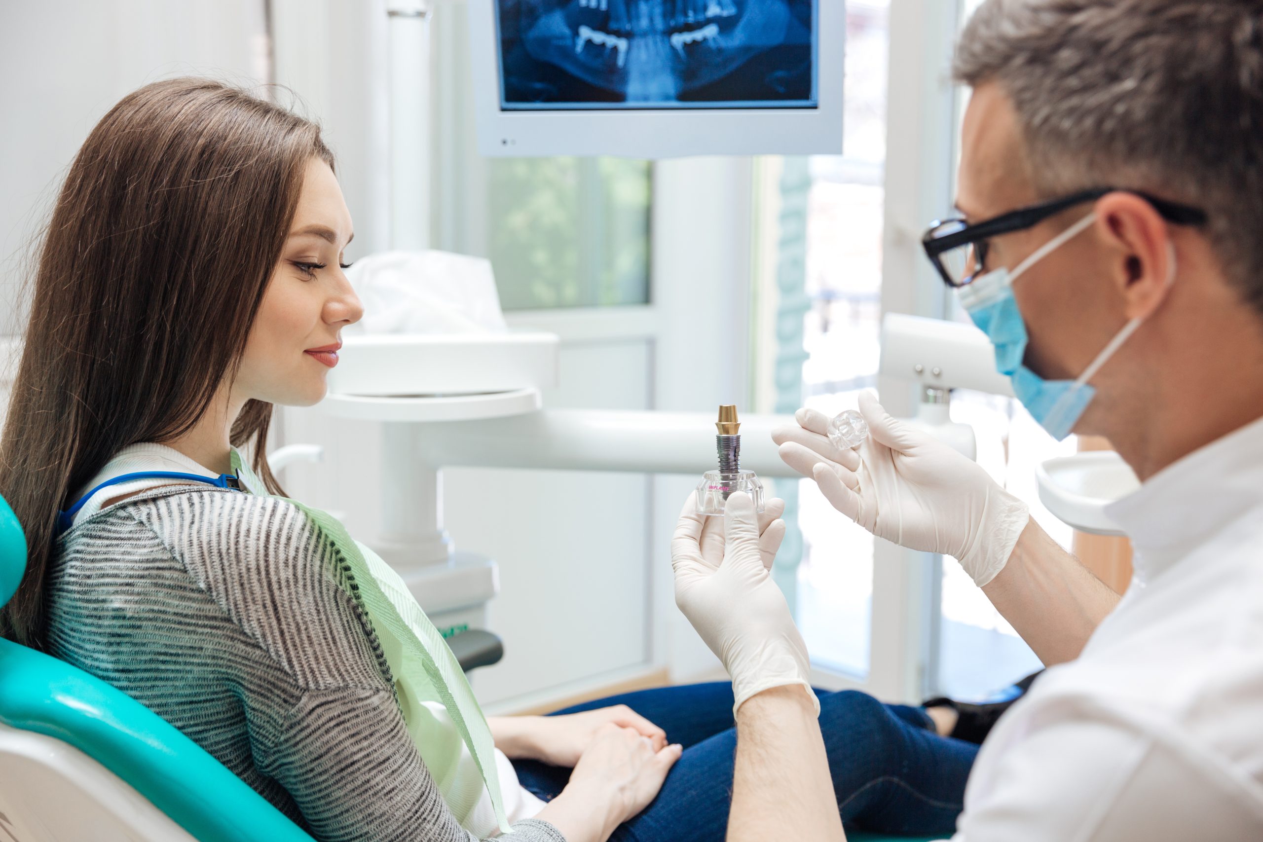Dr.Favia showing woman dental implant at his office.
